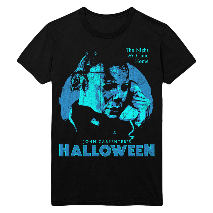 A black short-sleeve graphic t-shirt featuring a stylized blue and cyan print of Michael Myers from John Carpenter's Halloween, with the text 'The Night He Came Home' and 'JOHN CARPENTER'S HALLOWEEN' on a white background.